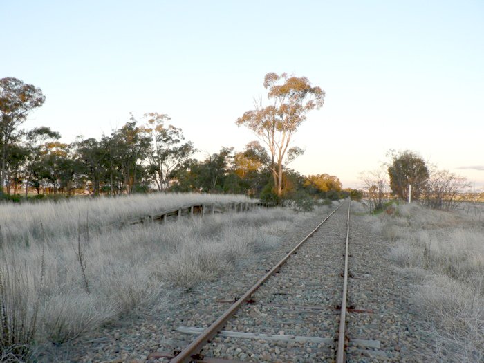 The view looking east. The loading bank is visible on the left. On the right the passenger platform remains are marked with the half-kilometre post.