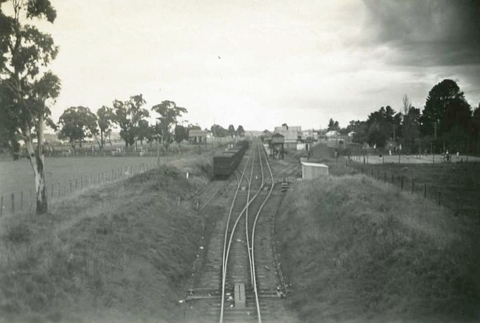 The view looking down the line towards the station. A set of stock wagons are visible in the sidingon the left. On the right of the line can be seen the elevated water tank and the station building beyond.