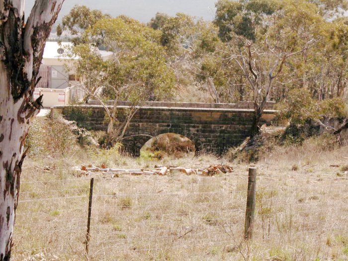The line once passed under Mudgee Road at this single track overbridge. TOday neither rail nor public road uses the bridge; it is part of the driveway to a local landscape supply business.
