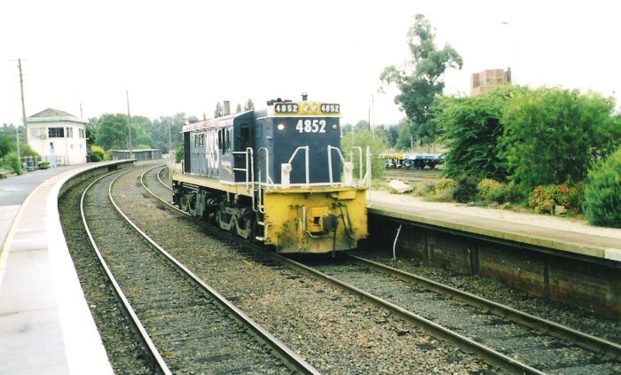 4852 has had to run past Bathurst East Box and switch onto the road passing the former down platform. The old gasworks building is seen in the right background.