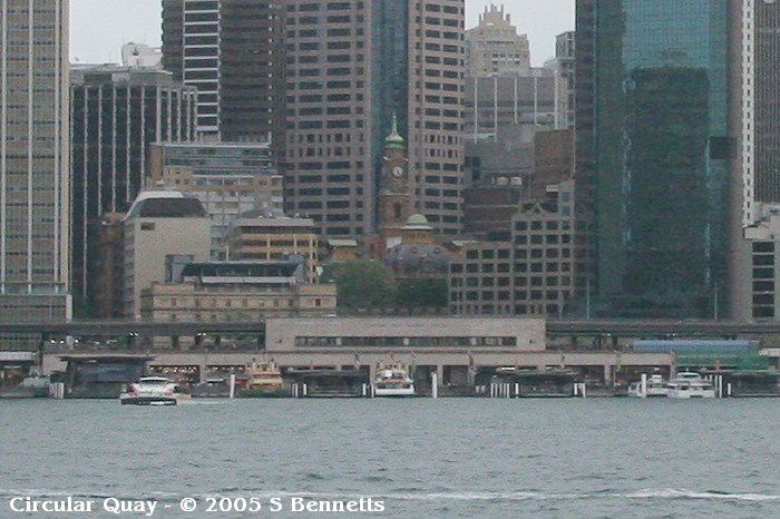 A view showing Circular Quay Station from the front side. The photo was taken from across the harbour at Milsons Point, underneath the Harbour Bridge.