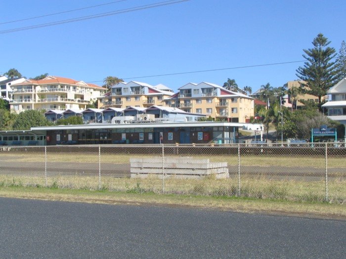 A trackside view of the station building framed by apartment buildings.