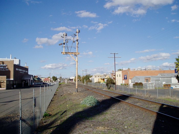 The view looking east towards the station, with an old semaphore signal gantry with the arms removed.