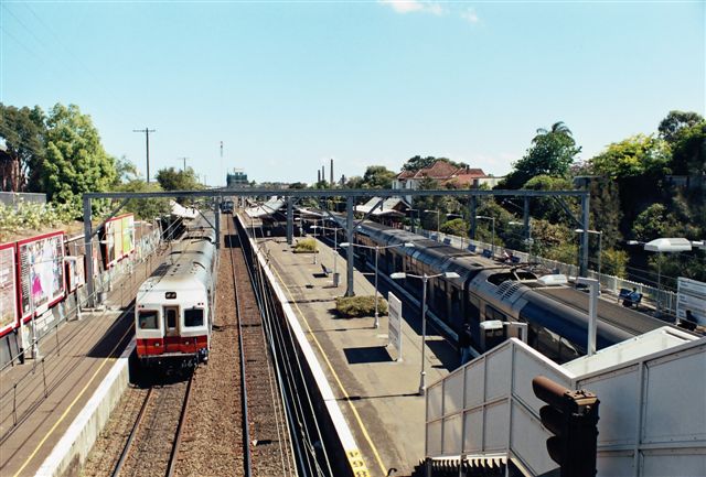 
Two passenger trains are passing throught the station, with an up freight
train approaching from the south in the distance.

