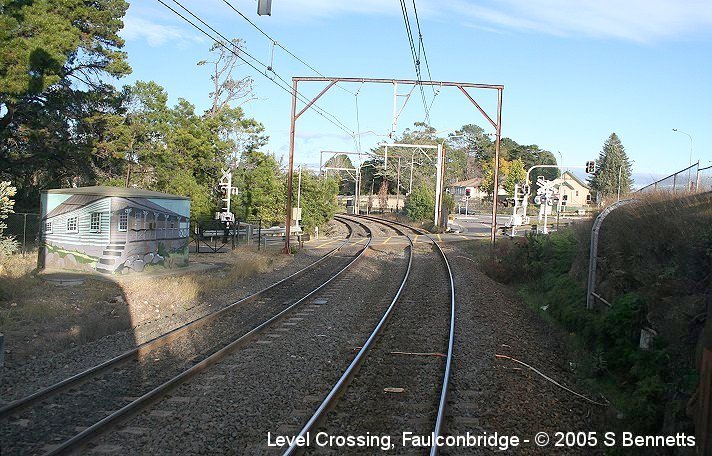 A view of the level crossing at Faulconbridge taken from the rear of a Sydney bound train. To the left of photo can be seen the Comms Hut which has been painted by April Keogh with a painting of Henry Parkes first house in Faulconbridge which is located nearby.