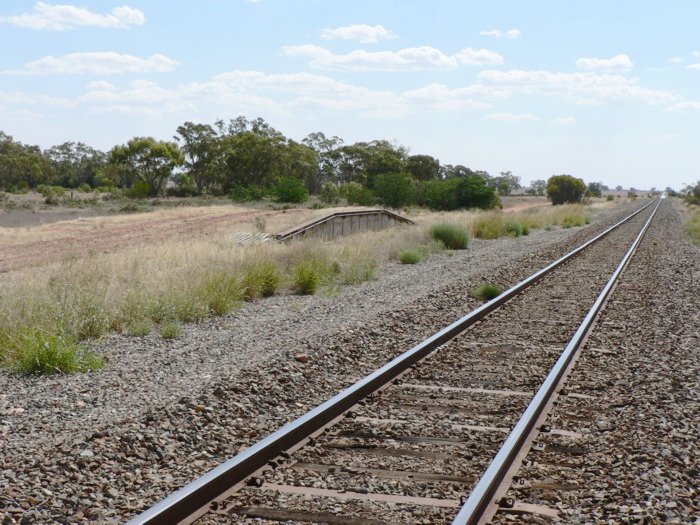 The view looking west. The former goods siding and loop line have been lifted.  The former station was located opposite the loading bank.