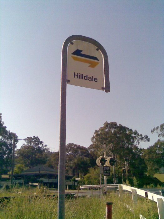 The Hilldale Station sign on the street, with level crossing in the background.