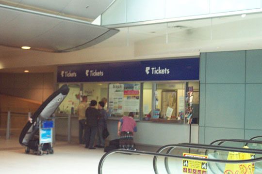
The ticket counter of the International Airport station. Ticket machines are
on the opposite side.  Escalators lead up to the Arrivals level of the airport.
