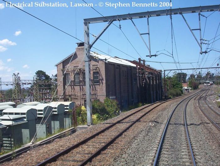 
The electrical substation located west of Lawson station,  which can be seen
in the distance.  This substation caught fire in 2003 causing some
disruptions to Cityrail services for a number of days. Only one electric
train was allowed in the section between Springwood and Wentworth Falls on
the down main at a time until repairs were made. The roof is still missing
on part of the building furthest from camera.
