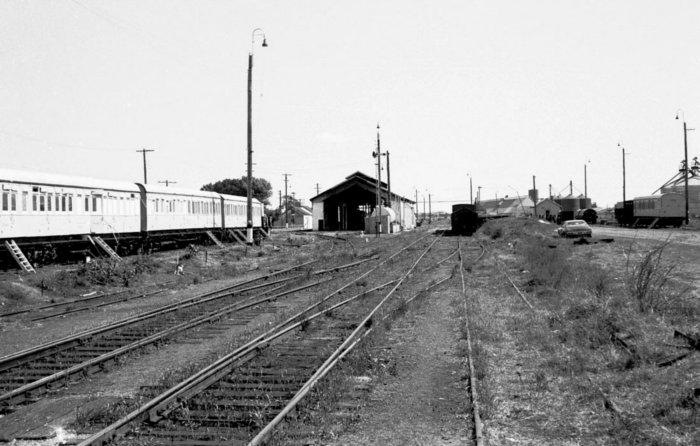 The view looking west through the yard. A set of passenger cars sits on the Perway Siding, with the engine shed visible in the distance.