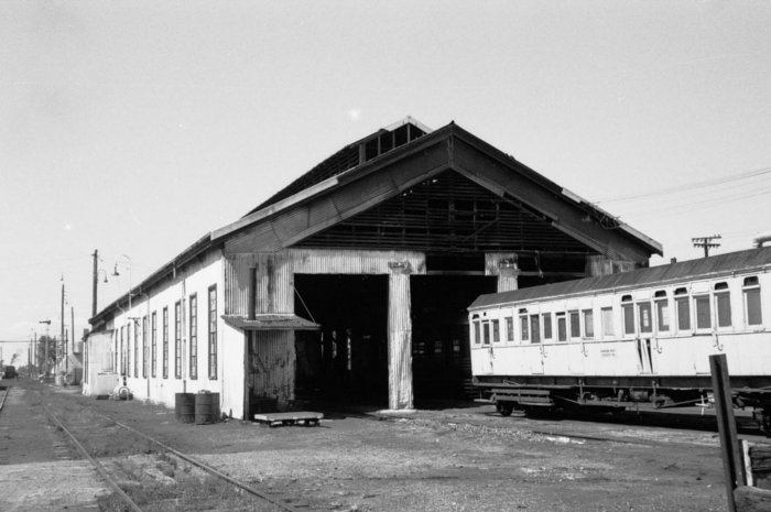 A passenger car sits just outside the engine shed in this view looking east.