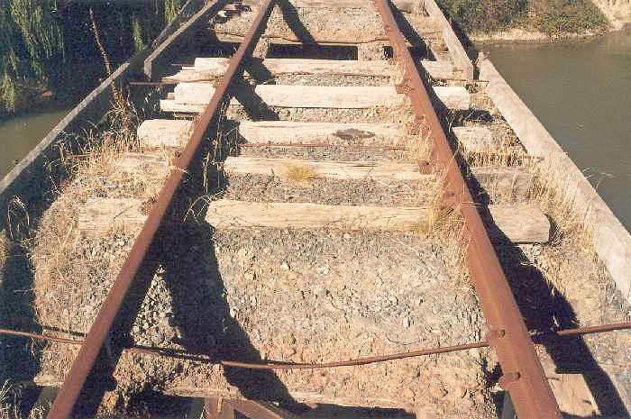 
A close-up of the ballasted decking on the Murrumbidgee Northern Canal bridge
showing where the timbers have deteriorated spilling the ballast into the
canal.
