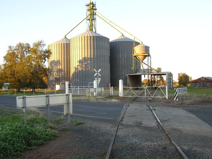 The broad gauge mainline crossing Urana-Oaklands Rd into a grain loading facility.