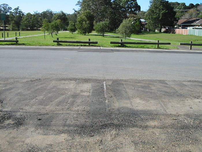 
The remains of the branch line, embedded in the road where it crosses
Vista Parade, Kotara South. The cycle track adjacent roughly follows the
line as it heads towards the Scholey Street Junction.
