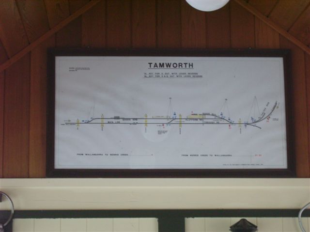 A photo through the glass of the former signal-box on the platform, showing the diagram of the former track arrangement. There is now a single track at the station. The main line then follows its former path in the left of the diagram , although the siding at the loading dock of a factory dis-used due to a switch to road transport.