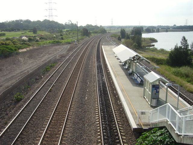The view looking west towards Sandgate. A view of the island platform from the footbridge that services it. The lines from left to right are the Down Coal, Up Coal (to Port Waratah) , Down Main and Up main. This station was constructed (and squeezed in by slewing the lines) after many years of campaigning by the University of Newcastle for a commuter station  for staff and students.