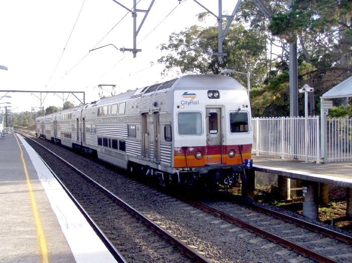 A northbound train flies through Warnervale Station.